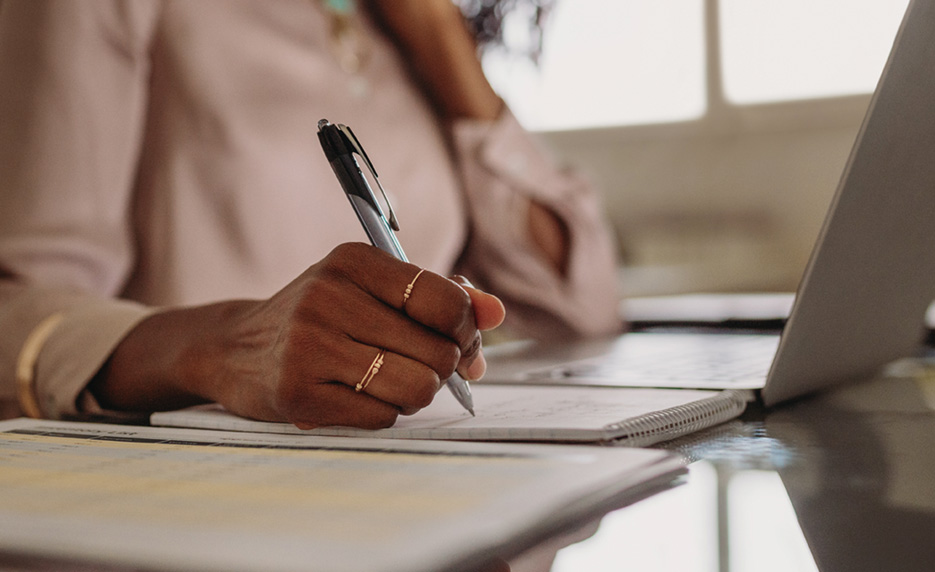 woman writing on pad of paper